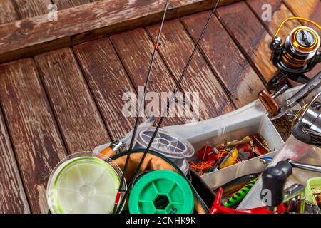Diverse tegole da pesca con verga e bobine su sfondo marrone di legno. Mockap per la pubblicità e la pubblicazione. Foto Stock