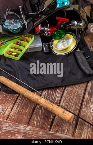 Diverse tegole da pesca con verga e bobine su sfondo marrone di legno. Mockap per la pubblicità e la pubblicazione. Foto Stock