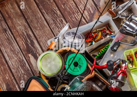 Diverse tegole da pesca con verga e bobine su sfondo marrone di legno. Mockap per la pubblicità e la pubblicazione. Foto Stock
