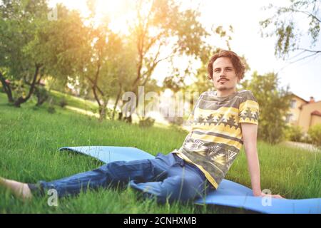 bell'elegante ragazzo ama la natura e sogna qualcosa che si siede nel parco. vista tranquilla Foto Stock