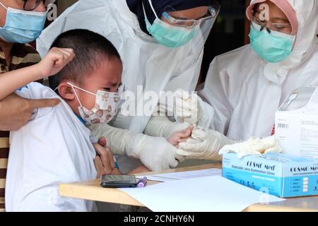 Tangerang meridionale, Indonesia. 18 Settembre 2020. Un medico preleva un campione di sangue da un bambino per il test COVID-19 nelle zone residenziali di Tangerang meridionale, Indonesia, il 18 settembre 2020. I casi COVID-19 in Indonesia sono saliti di 3,891 in un giorno a 236,519, con il numero dei decessi che si è aggiunto da 114 a 9,336, secondo il ministero della salute di venerdì. Credit: Veri Sanovri/Xinhua/Alamy Live News Foto Stock