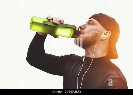 Muscolare atleta barbuto bere un acqua dopo una buona sessione di allenamento sul parco della città. Foto Stock