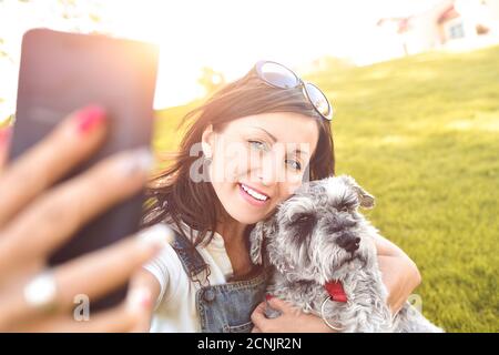 Ritratto di una felice donna caucasica che abbracca il suo amato cane e fa selfie con lui. Il concetto di amore per gli animali Foto Stock