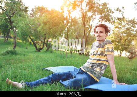 bell'elegante ragazzo ama la natura e sogna qualcosa che si siede nel parco. vista tranquilla Foto Stock