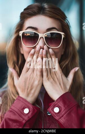 Primo piano ritratto di una bella ragazza sorridente in occhiali da sole con denti piacevoli divertirsi in strada. Foto Stock