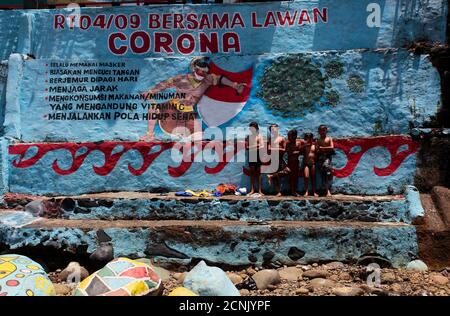 Bogor, Indonesia. 17 Settembre 2020. I bambini giocano nei pressi di un guerriero che combatte il murale del coronavirus su un muro a Bogor, Giava Occidentale, Indonesia, 17 settembre 2020. I murales servono anche a ricordare che gli sforzi contro il virus non sono più compiuti e che tutti hanno un ruolo nel seguire il protocollo sanitario. (Foto di Adriana/INA Photo Agency) Credit: Sipa USA/Alamy Live News Foto Stock