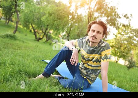 bell'elegante ragazzo ama la natura e sogna qualcosa che si siede nel parco. vista tranquilla. guarda nella macchina fotografica Foto Stock