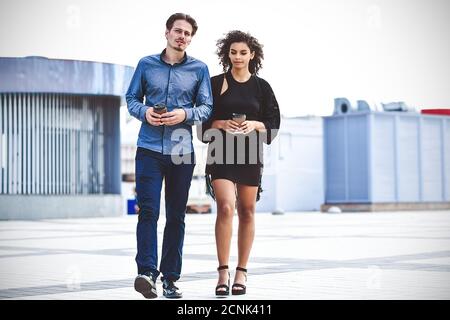 Incontro informale all'aperto in una giornata di sole. Coppia interracial a piedi in strada. Foto Stock