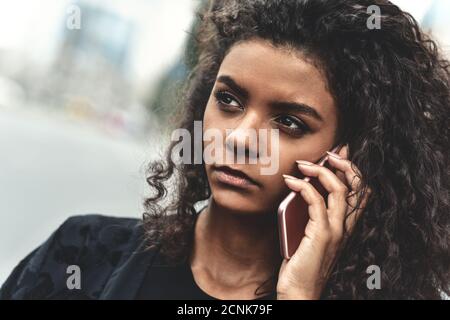 Emozioni negative. Concetto di stile di vita. Primo piano di una giovane donna di razza mista utilizzare un telefono. Foto Stock