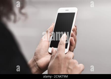 Primo piano mano di giovane razza mista donna di affari utilizzando telefono con Foto Stock