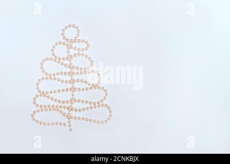 Perline in forma di albero di Natale su sfondo bianco. Composizione piatta per Natale, Capodanno. Spazio libero per la copia del testo. Foto Stock