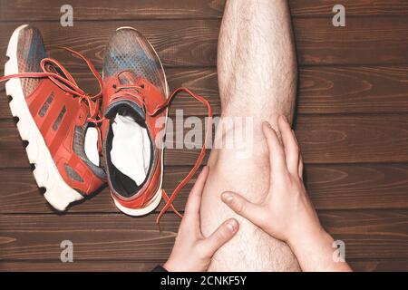giovane uomo sportivo con gambe atletiche forti che tengono il ginocchio con le sue mani in dolore dopo aver subito una lesione del legamento durante un esecuzione w Foto Stock