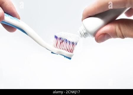 Dentifricio fresco e spazzolino da denti nelle mani maschili, isolato su sfondo bianco. Concetto sanitario Foto Stock