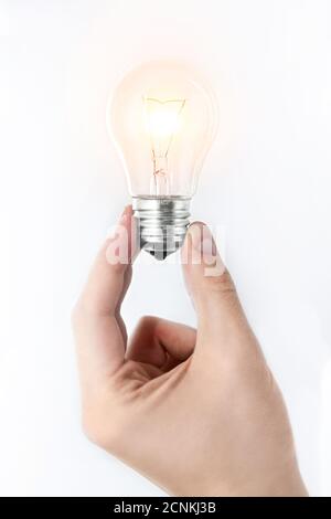 Una mano dell'uomo che tiene una lampadina luminosa su uno sfondo bianco. Idea concetto Foto Stock