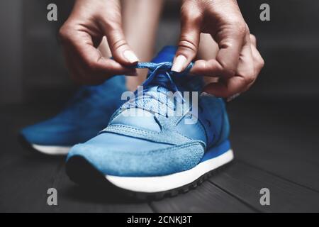 Donna si lega alle scarpe da ginnastica. Vista ravvicinata. Concetto di stile di vita sano. La ragazza misura nuove sneakers sportive in dres Foto Stock