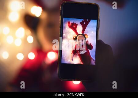 Il genitore scatta foto di un bambino con lo smartphone. Ricordi di famiglia digitali. Foto Stock