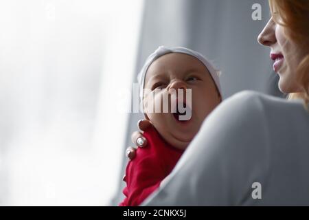 Madre che tiene la ragazza del bambino appena nata carina nelle sue braccia. Sonnolento baby yawning. Foto Stock