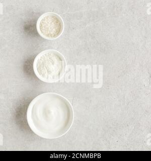 Tre prodotti cosmetici naturali in una ciotola: Crema viso, argilla cosmetica, sale marino su fondo di marmo grigio. Concetto di cura della pelle. Foto Stock