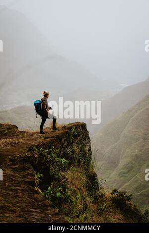 Femmina turistico che guarda giù la valle di Paul con splendida vista panoramica sulle alte catene montuose e la valle profonda. Foto Stock