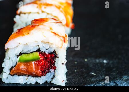 Primo piano di maki roll con tobiko, avocado, salmone, gamberi e formaggio cremoso Foto Stock
