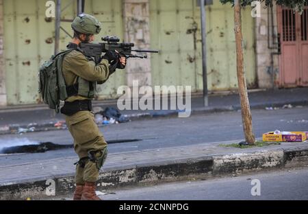 Hebron, gli insediamenti ebraici e gli accordi di normalizzazione di Israele con gli Emirati Arabi Uniti e il Bahrein. 18 Settembre 2020. Un soldato israeliano punta la sua arma ai manifestanti palestinesi durante gli scontri, a seguito di una protesta contro l'espansione degli insediamenti ebraici e gli accordi di normalizzazione di Israele con gli Emirati Arabi Uniti e il Bahrain, nella città di Hebron, in Cisgiordania, il 18 settembre 2020. Credit: Mamoun Wazwaz/Xinhua/Alamy Live News Foto Stock