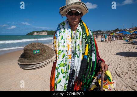 Il venditore di strada vende cappelli e kangas ( abbigliamento ) alla spiaggia di Ponta Negra, città natale, Rio Grande do Nortte state, Brasile nordorientale. Foto Stock