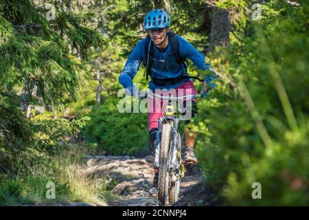 Uomo in mountain bike lungo un sentiero nelle Alpi austriache, Saalbach, Austria Foto Stock