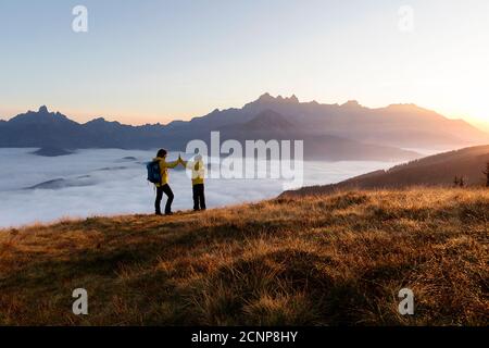 Madre e figlio in piedi sulla montagna Rossbrand, dando alte cinque all'alba Foto Stock