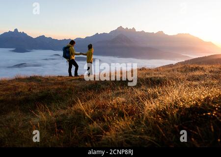 Madre e figlio che tengono le mani mentre si levano in piedi sul Rossbrand montagna all'alba Foto Stock