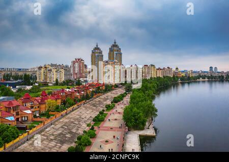 Vista aerea sul fiume Dnepr con cielo nuvoloso e quartiere di case nella verde Obolon zona della città di Kiev. Scatto con drone volante. Foto Stock