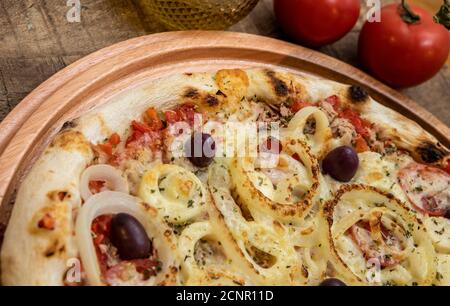 Tonno pizza italiana servita senza taglio su una tavola di legno in una cucina o pizzeria Foto Stock