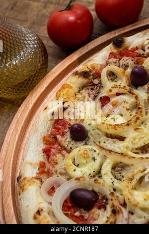 Tonno pizza italiana servita senza taglio su una tavola di legno in una cucina o pizzeria Foto Stock