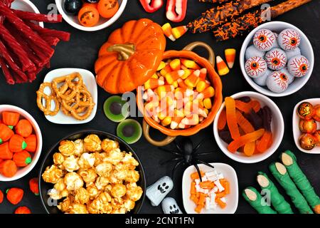 Halloween caramella scena del tavolo a buffet su uno sfondo di pietra nera. Assortimento di dolci e dolci. Vista dall'alto. Foto Stock