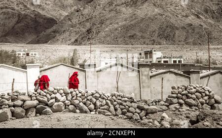 Monastero di Thiksay nel villaggio di Thiksey, India – 20 agosto 2016: Il gruppo di monaci tibetani in tombi rossi passa dal paesaggio incolore nel villaggio di Thiksey Foto Stock