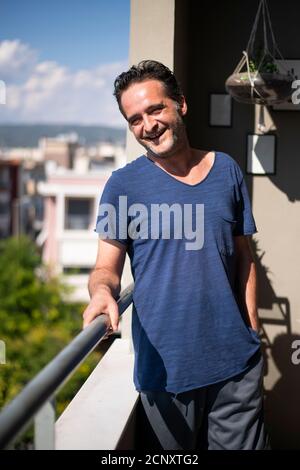 Ritratto di un uomo felice maturo sorridente al balcone. Concetto domestico Foto Stock