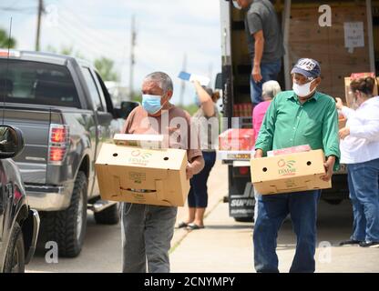 El Cenizo, Texas USA 17 settembre 2020: I volontari locali distribuiscono scatole di cibo ai residenti della colonia di El Cenizo circa 10 miglia a sud di Laredo lungo il confine tra Texas e Messico. Circa 450 famiglie vengono servite due volte alla settimana con prodotti di base e frutta fresca in uno sforzo sponsorizzato dalla Missione Luterana Latinoamericana (LALM). A causa della pandemia del coronavirus, la distribuzione è ora un evento drive-through socialmente distanziato, con volontari e clienti che indossano tutti i rivestimenti del viso. Credit: Bob Daemmrich/Alamy Live News Foto Stock