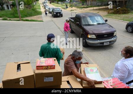 El Cenizo, Texas USA 17 settembre 2020: I volontari locali distribuiscono scatole di cibo ai residenti della colonia di El Cenizo circa 10 miglia a sud di Laredo lungo il confine tra Texas e Messico. Circa 450 famiglie vengono servite due volte alla settimana con prodotti di base e frutta fresca in uno sforzo sponsorizzato dalla Missione Luterana Latinoamericana (LALM). A causa della pandemia del coronavirus, la distribuzione è ora un evento drive-through socialmente distanziato, con volontari e clienti che indossano tutti i rivestimenti del viso. Credit: Bob Daemmrich/Alamy Live News Foto Stock