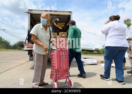 El Cenizo, Texas USA 17 settembre 2020: I volontari locali distribuiscono scatole di cibo ai residenti della colonia di El Cenizo circa 10 miglia a sud di Laredo lungo il confine tra Texas e Messico. Circa 450 famiglie vengono servite due volte alla settimana con prodotti di base e frutta fresca in uno sforzo sponsorizzato dalla Missione Luterana Latinoamericana (LALM). A causa della pandemia del coronavirus, la distribuzione è ora un evento drive-through socialmente distanziato, con volontari e clienti che indossano tutti i rivestimenti del viso. Credit: Bob Daemmrich/Alamy Live News Foto Stock