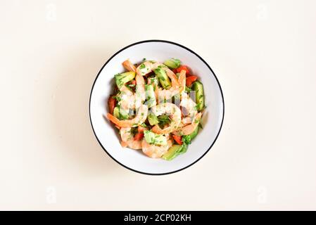 Avocado, gamberi, insalata di pomodoro con verdure in ciotola su sfondo di pietra chiaro con spazio libero per il testo. Concetto di alimentazione sana. Vista dall'alto, disposizione piatta Foto Stock