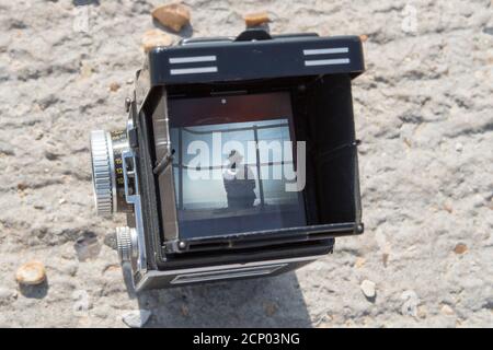 Una fotocamera reflex doppia Rolleiflex vintage che incornicia un soggetto una scena da spiaggia nel mirino Foto Stock