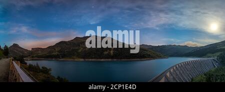 Lago con le montagne durante l'ora blu nelle Alpi francesi. Foto Stock