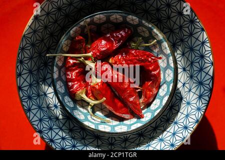 Mortara 09/15/2020: Peperoncini rossi secchi in un recipiente di stile giapponese e piatto rosso Foto Stock