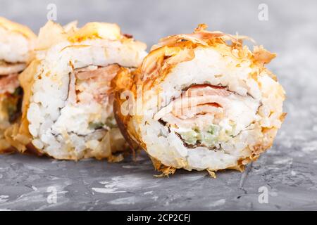 Involtini giapponesi di sushi maki con tonno, cetriolo, formaggio su fondo nero di cemento. Vista laterale, primo piano, macro. Foto Stock