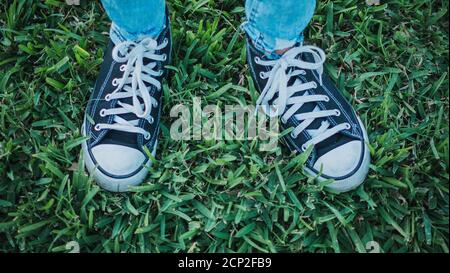 Persona in piedi sull'erba e indossa le sneakers nere Foto Stock