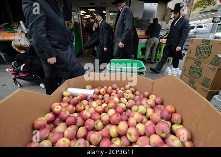 New York City, Stati Uniti. 18 Settembre 2020. gli ebrei ortodossi passano davanti a un grande contenitore di mele mentre la gente acquista prima dell'inizio del nuovo anno ebraico "Rosh Hashanah. Nella sezione Williamsburg del quartiere Brooklyn di New York City, NY, 18 settembre 2020. Rosh Hashanah segna la prima delle Giornate Suore Ebraiche, è osservato con celebrazioni, pregando in sinagoga, il suono dello Shofar (corno di montone), e mangiando cibi simbolici come le mele immerse nel miele per evocare un dolce Capodanno. (Anthony Behar/Sipa USA) Credit: Sipa USA/Alamy Live News Foto Stock