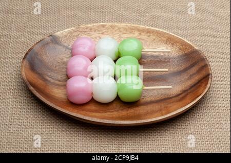 Dolce tradizionale giapponese chiamato Dango Mochi su piatto di legno. Isolato su sfondo juto. Primo piano. Vista dall'alto. Shot orizzontale. Foto Stock