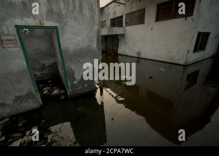 Edifici di magazzino sommersi su un'area costiera che soffre di cedimenti di terra e inondazioni di acqua di mare. Foto Stock