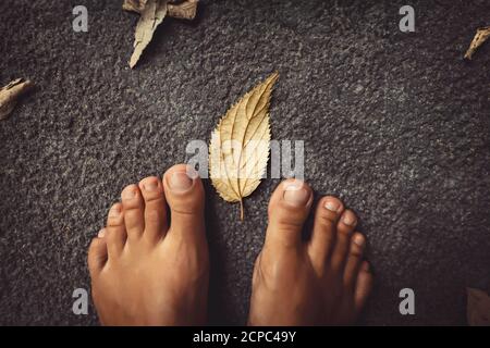 Benvenuto autunno sfondo. Closeup Concept Foto di una donna a piedi nudi piedi e foglie secche. Tema della stagione autunnale. Foto Stock
