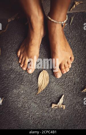 Benvenuto autunno sfondo. Closeup Concept Foto di una donna a piedi nudi piedi e foglie secche. Tema della stagione autunnale. Foto Stock