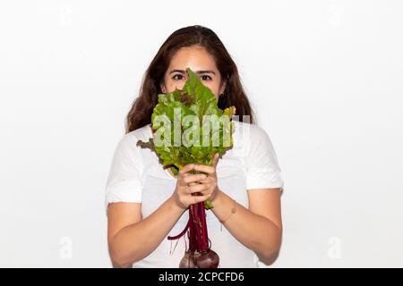 Vero giovane uomo con un mazzo di ravanelli che ricoprono il viso. Isolato su sfondo bianco. Spazio di copia Foto Stock